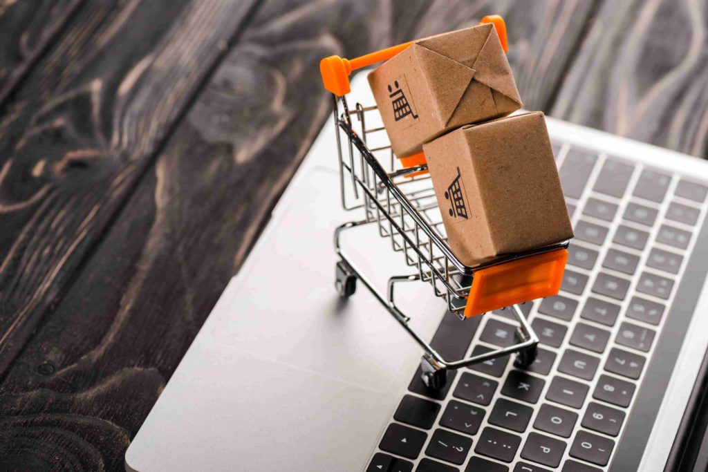 Comercio online - carrito con cajas encima de una laptop